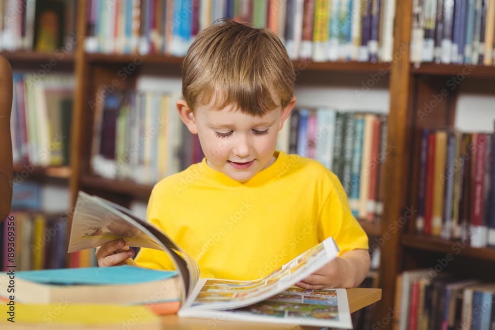 Cute pupil reading book in the library Cute pupil reading book in the library