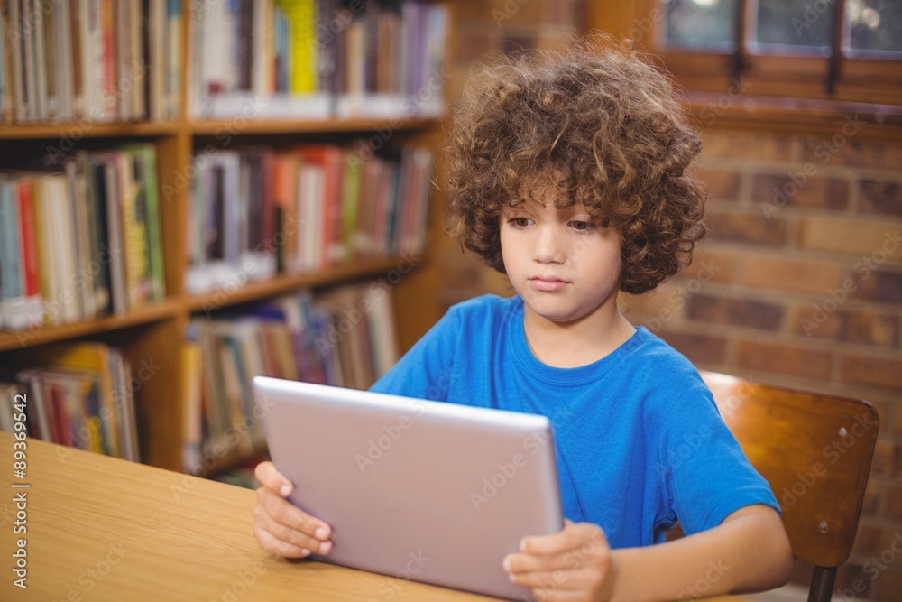 Cute pupil using tablet in the library Cute pupil using tablet in the library