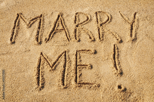 The words Marry Me written in the sand on the beach