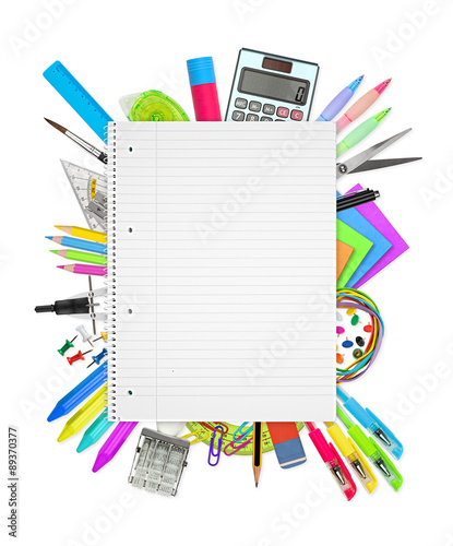office / school supplies under spiral-bound notebook isolated on white background