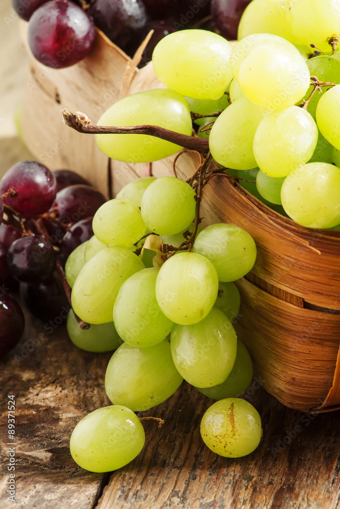 Green grapes in a wicker basket in a rustic style, selective foc Green grapes in a wicker basket in a rustic style, selective foc