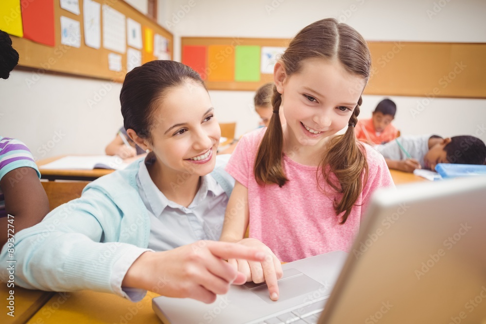 Teacher using laptop with pupil Teacher using laptop with pupil