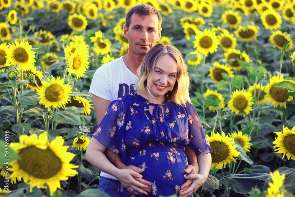 Happy couple - Husband and his pregnant wife in a field of sunflowers Happy couple - Husband and his pregnant wife in a field of sunflowers
