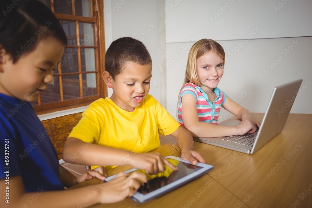 Cute pupils in class using laptop and tablet Cute pupils in class using laptop and tablet