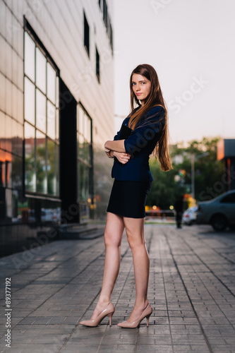 Successful businessman smiling, standing on the background of buildings and holding a tablet computer. City business woman working. © ruslan1117