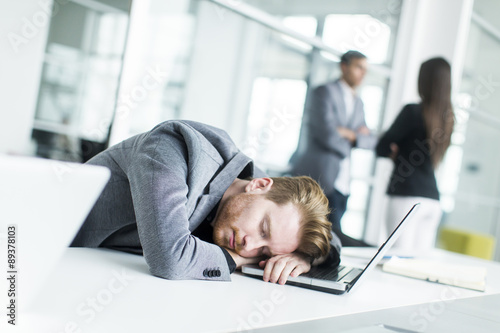 Canvas Print Tired young man sleeping in the office