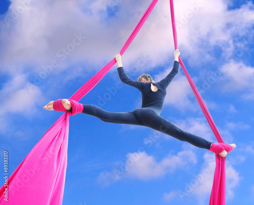 cheerful child training on aerial silks in the sky
