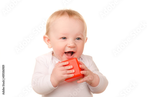 baby boy in white playing with toy red block