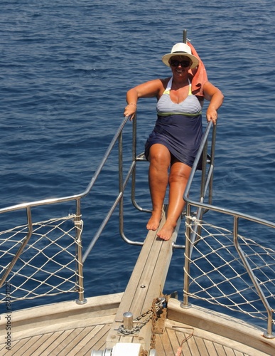 A mature woman wearing sunglasses and a hat while on a boat trip during a vacation in turkey