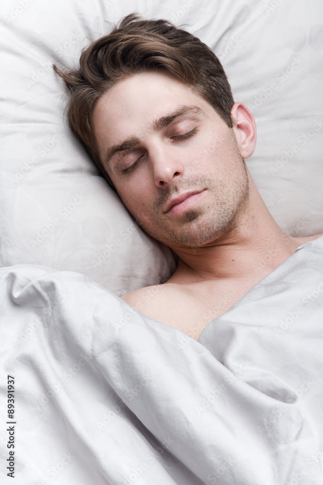 Young handsome man sleeping in bed