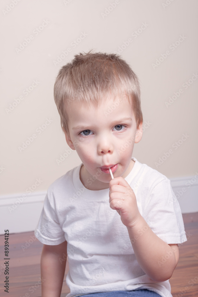 little boy in white tshirt sucking lollipop in his mouth little boy in white tshirt sucking lollipop in his mouth