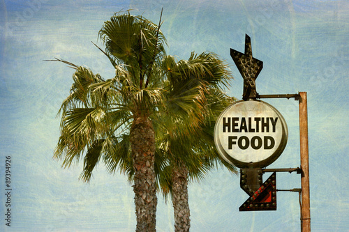 aged and worn vintage photo of healthy food sign with palm trees