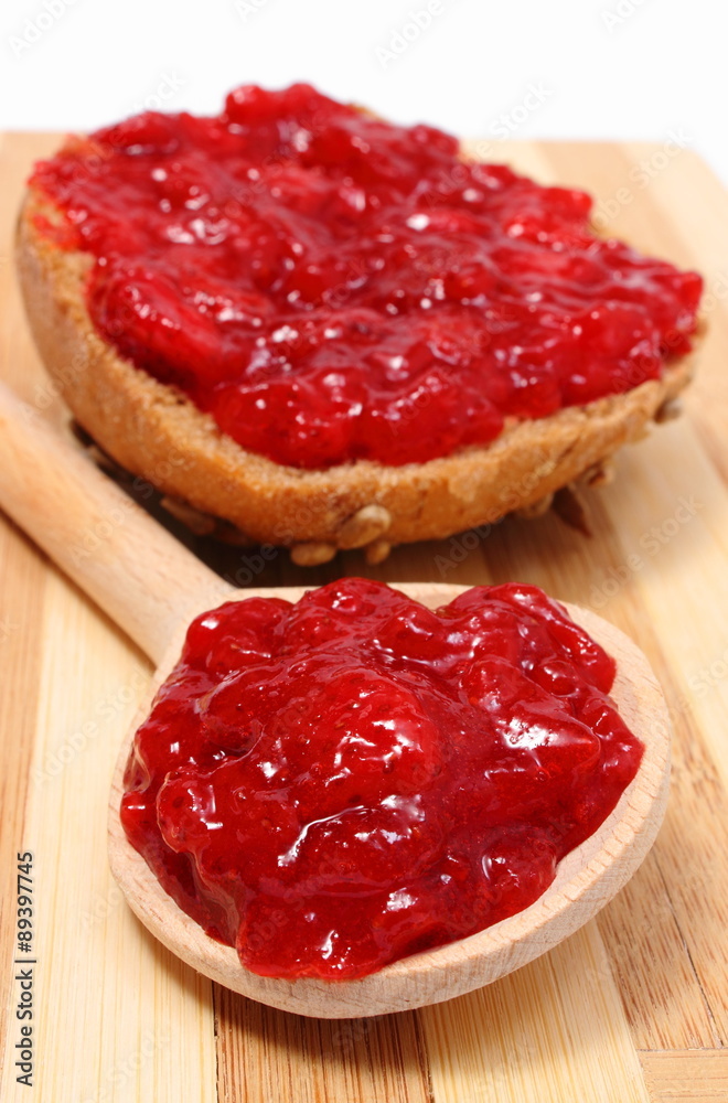 Strawberry jam on wooden spoon and whole wheat bread Strawberry jam on wooden spoon and whole wheat bread