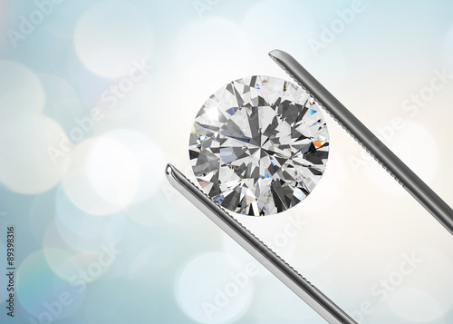 Luxury diamond in tweezers closeup with bright bokeh background