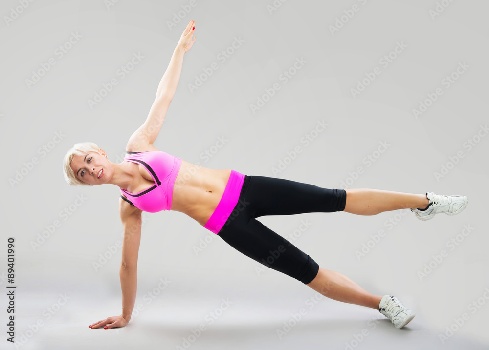 Sportive woman doing exercises, studio shot, gray background Sportive woman doing exercises, studio shot, gray background