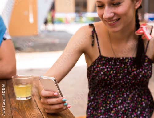 Young woman with telephone Portrait of cheerful girl using white smart phone browsing internet colourful nail art summer leisure dress open street cafe desk drink glass outdoor