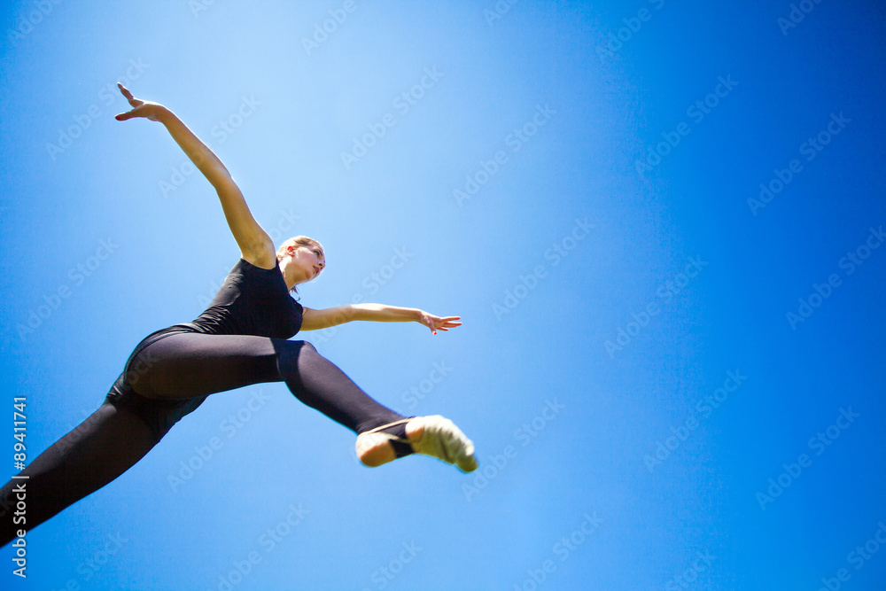 Smiling young gymnast is jumping in split and floating above the Smiling young gymnast is jumping in split and floating above the