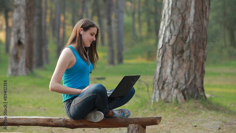 Young beautiful woman speaking and working using laptop in nature