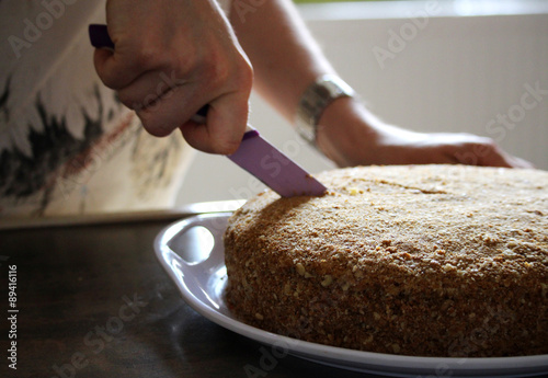 Woman is cutting honey cake with a knife
