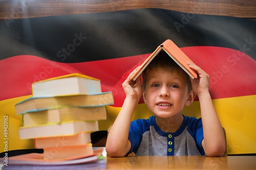 Composite image of cute boy with book on head