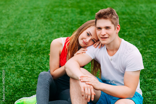 Young athletic couple sitting on the grass