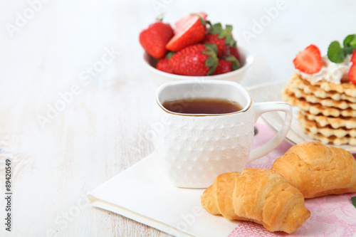 Tea with croissants and fresh strawberries on the table