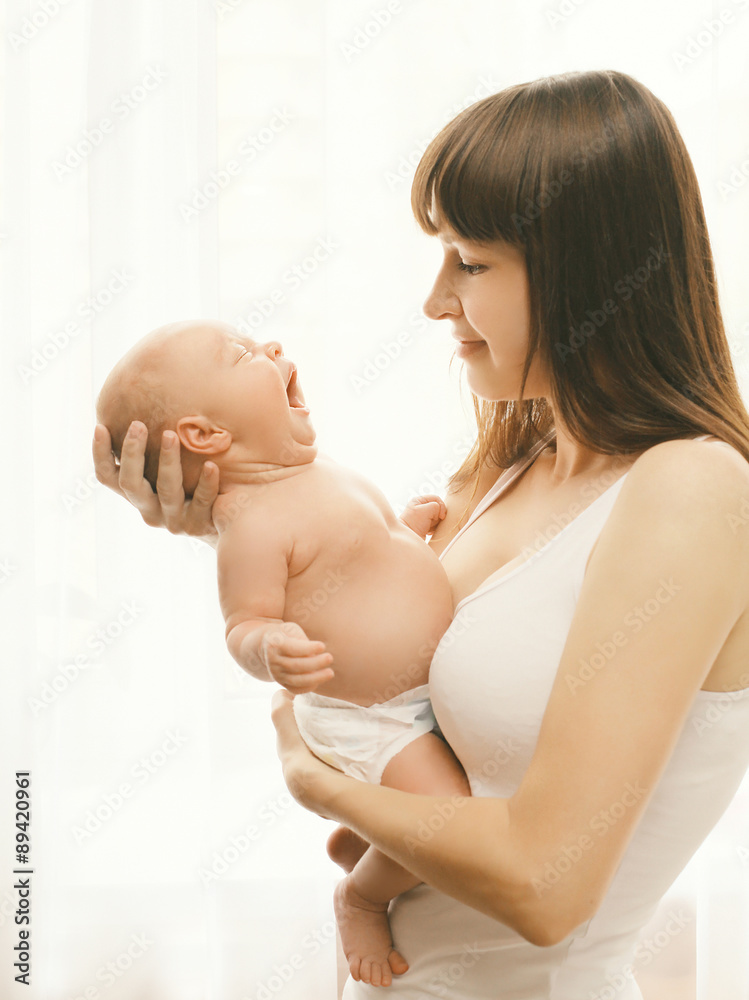 Portrait of baby yawning on hands of mother at home