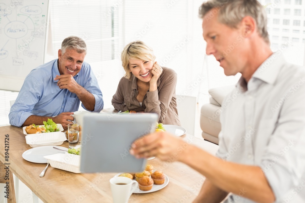 Casual business people looking at tablet while lunch Casual business people looking at tablet while lunch