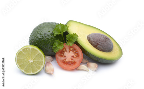 Fresh avocado surrounded by  tomato, garlic and lime on white background