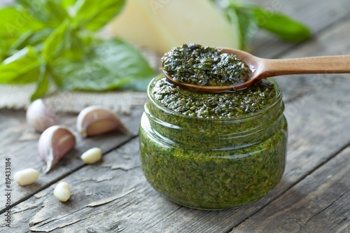 Photo Gourmet traditional Italian pesto in glass jar with wooden spoon