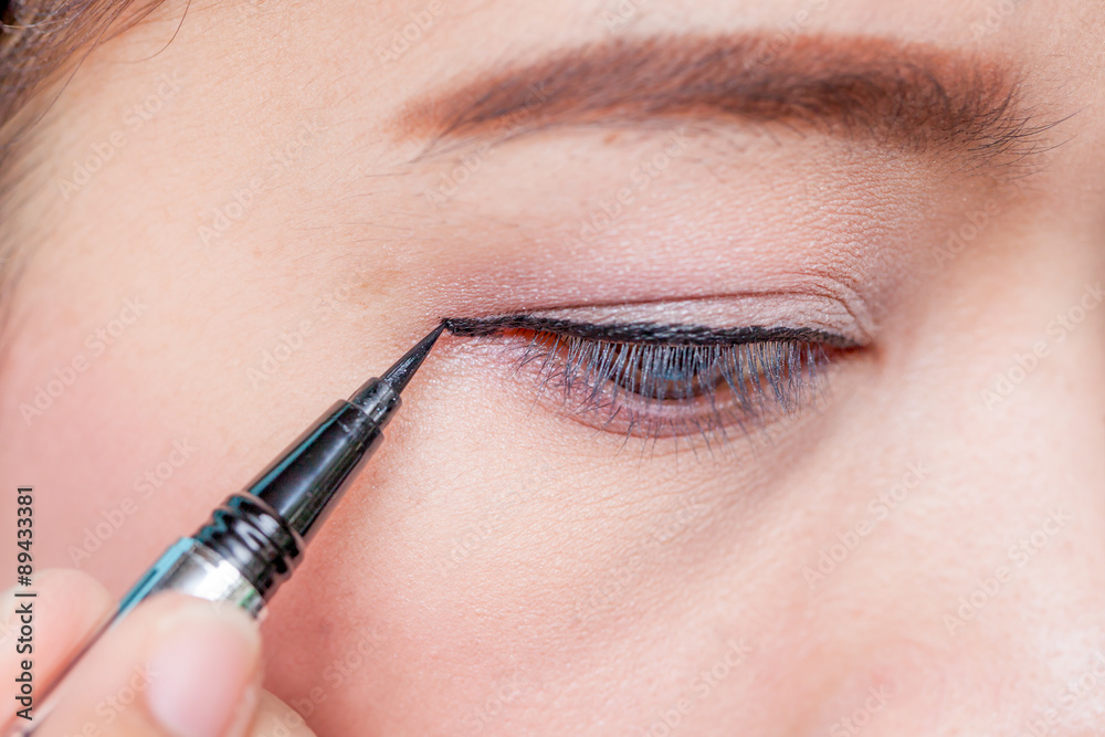 Makeup concept, Closeup asian woman applying eyeliner on eye