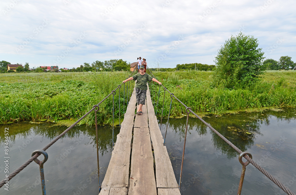 Fototapeta premium People walk on suspension bridge over the river