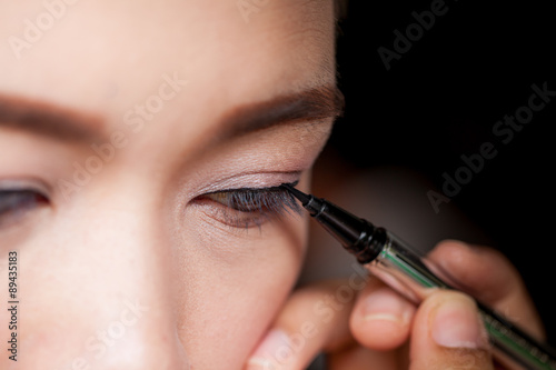 Makeup concept, Closeup asian woman applying eyeliner on eye photo