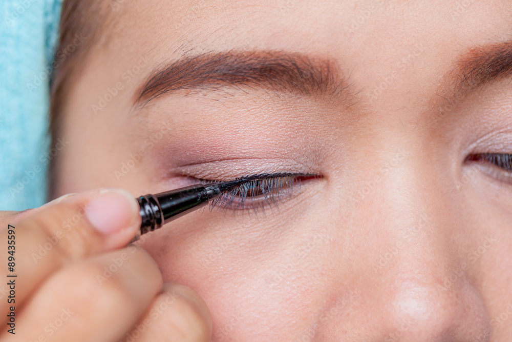 Makeup concept, Closeup asian woman applying eyeliner on eye