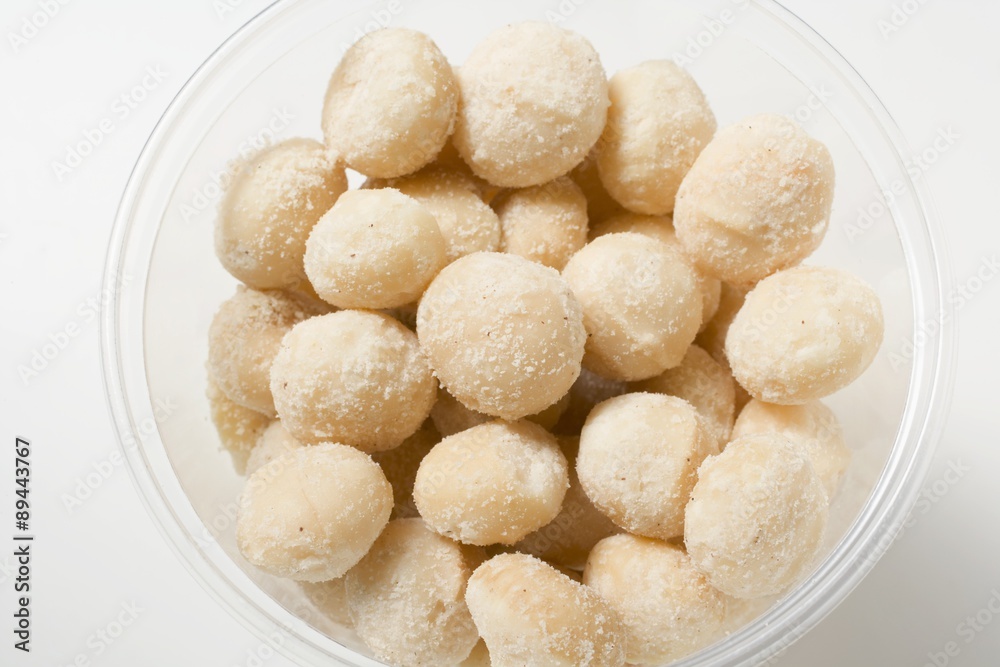 Salted macadamia nuts in plastic tub Salted macadamia nuts in plastic tub