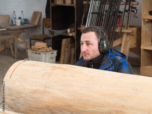 Ein Schreiner zersägt mit einer Kettensäge einen Baumstamm in seiner Werkstatt