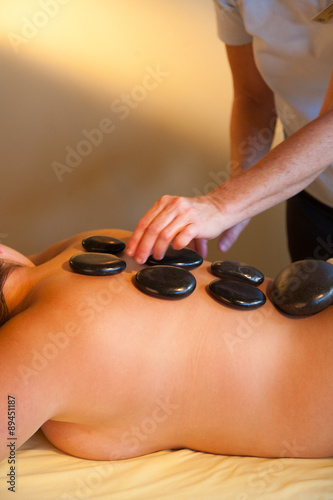 Adult woman receiving a hot rocks spa treatment on her back.