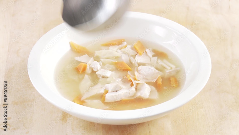 Broth being poured over small pieces of vegetables and chicken breast Broth being poured over small pieces of vegetables and chicken breast