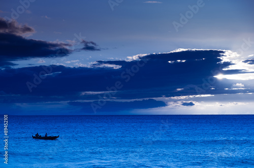 Fototapeta Naklejka Na Ścianę i Meble -  Two men paddling a Hawaiian outrigger canoe at sunset, Maui, Haw