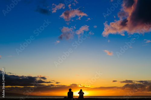 Couple watching the sunset on a beach in Maui Hawaii USA