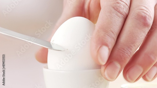 A breakfast egg being cut with a knife and salted