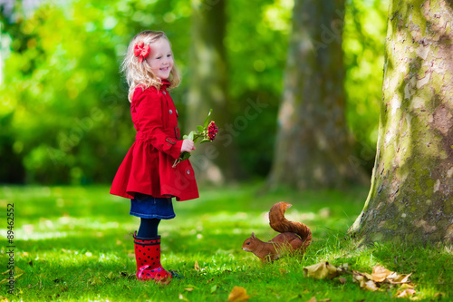 Little girl feeding a squirrel in autumn park