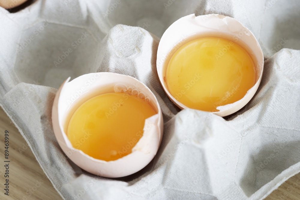 Two broken eggs in their shells in egg box Two broken eggs in their shells in egg box