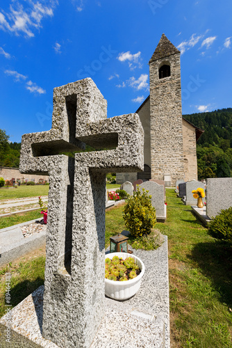Granite Cross in an Italian Mountain Cemetery / White granite cross in a cemetery with church. Pinzolo, Trento Italy 