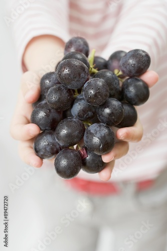 Child holding red grapes