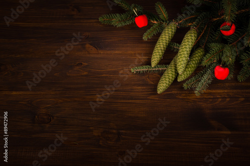 Spruce branch with cone and small red apples on wooden planks