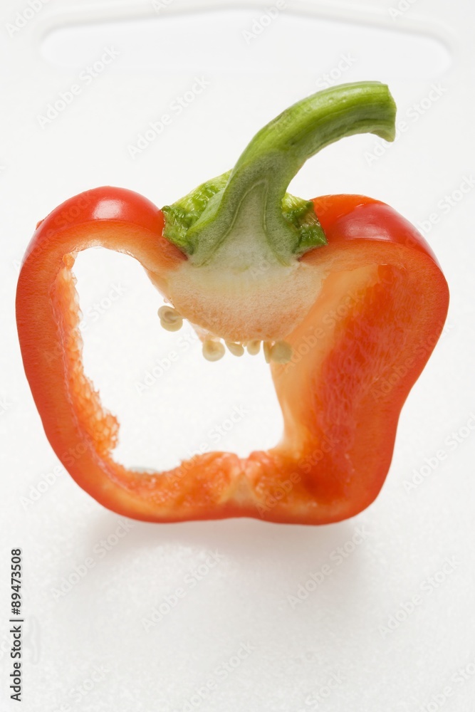 Slice of red pepper with stalk on chopping board Slice of red pepper with stalk on chopping board