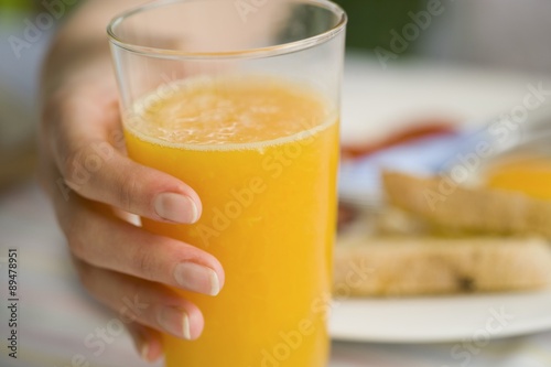 Hand holding a glass of orange juice