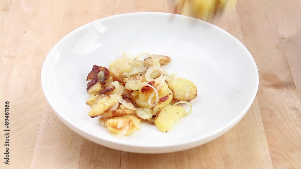Fried potatoes with onions being arranged on a plate Fried potatoes with onions being arranged on a plate