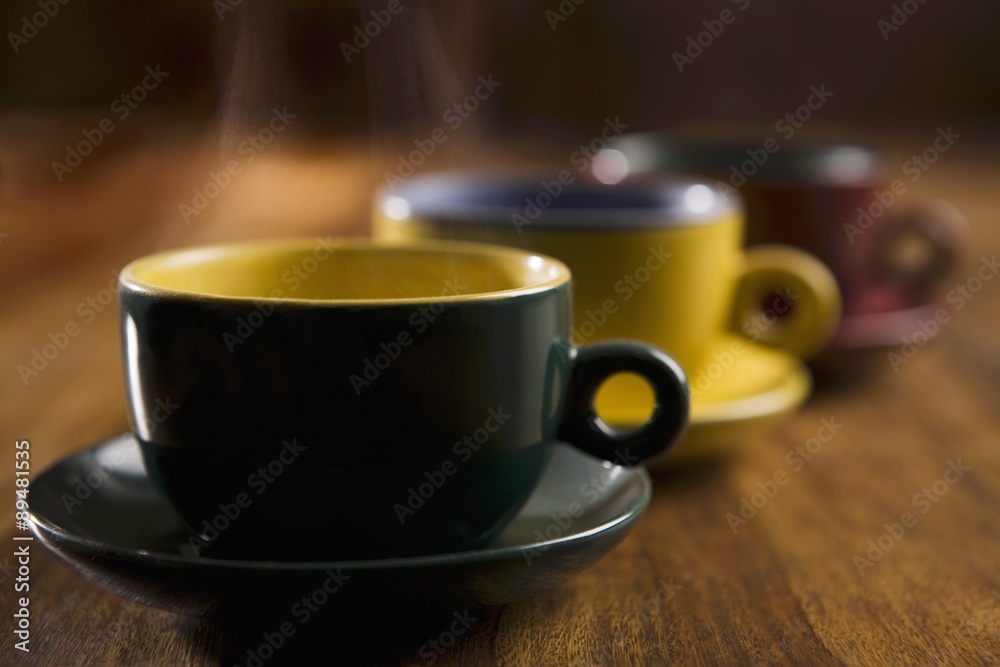 Steaming tea or coffee in three coloured cups and saucers Steaming tea or coffee in three coloured cups and saucers
